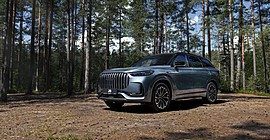 Jaecoo J8: вид спереди сбоку в лесу