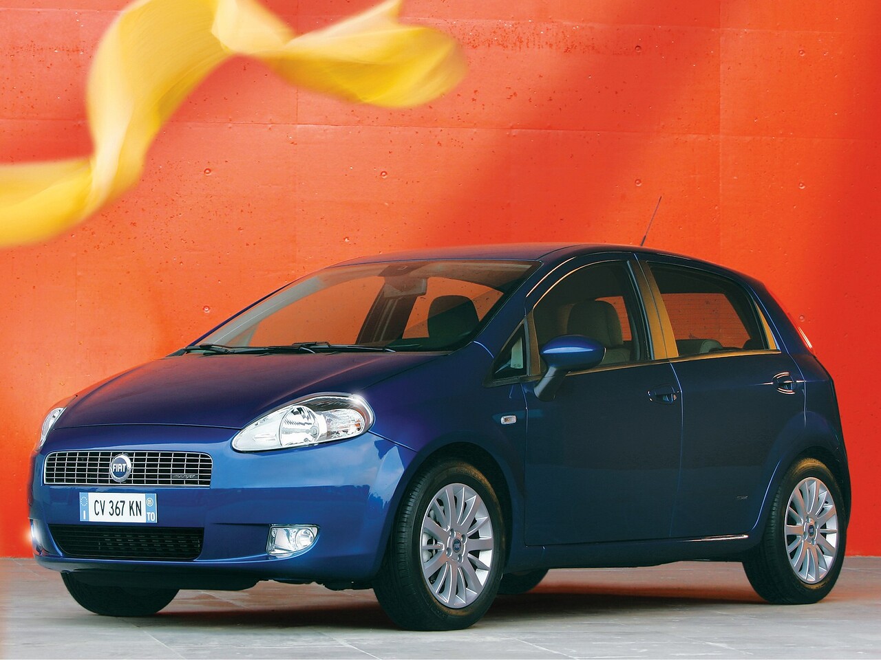 FIAT Grande Punto хэтчбек 5-дв. (III поколение, 2005 - 2012 г.в.): Три четверти спереди в студии на ярком оранжевом фоне