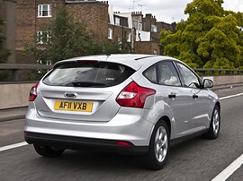 Ford Focus хэтчбек 5-дв. (III поколение, 2011 - 2015 г.в.): Три четверти сзади в движении по городу, серебристый кузов