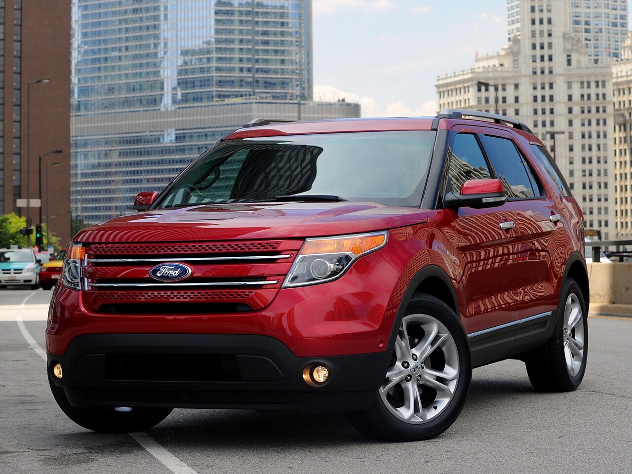 Ford Explorer 3.5 AT Sport: Три четверти спереди на фоне небоскрёбов, красный кузов
