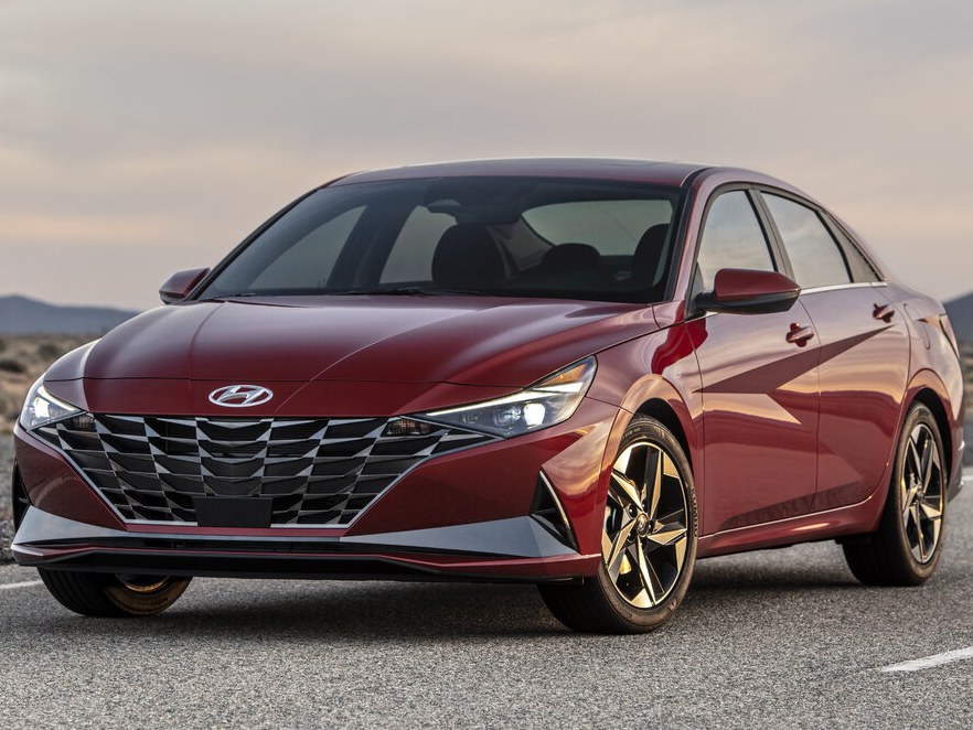 Hyundai Elantra седан 2.0 AT Comfort: Красный седан в пустынном пейзаже на закате, вид спереди сбоку