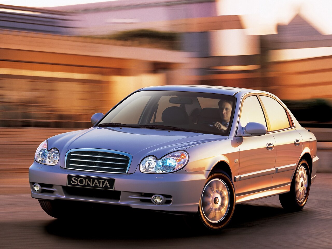 Hyundai Sonata (IV поколение, 2001 - 2010 г.в.): Серебристый седан в движении по дороге, вид спереди сбоку