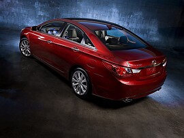 Hyundai Sonata (VI поколение, 2010 - 2015 г.в.): Красный седан у современного здания, боковой профиль