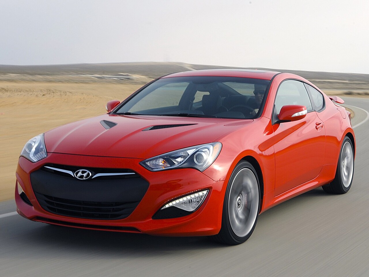 Hyundai Genesis купе 2.0 AT Performance: Красное купе в пустыне, вид спереди сбоку