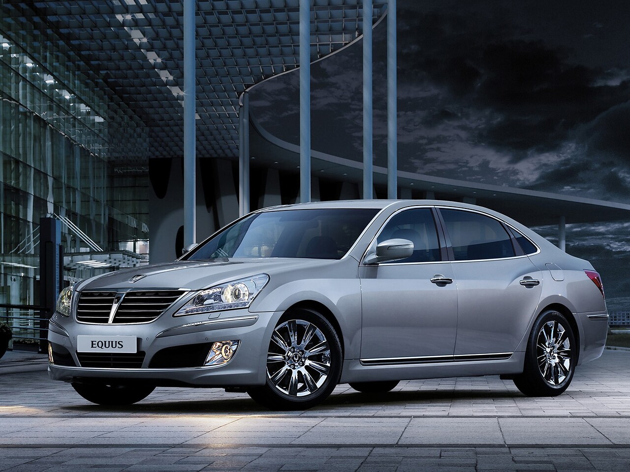 Hyundai Equus (II поколение, 2009 - 2013 г.в.): Серебристый седан у стеклянного здания в сумерках, вид спереди сбоку