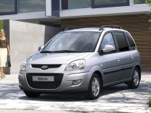 Hyundai Matrix: Серебристый минивэн у современного здания ночью, вид спереди сбоку