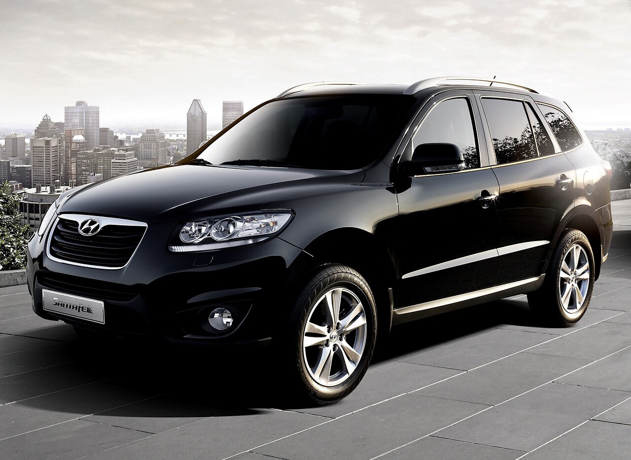 Hyundai Santa Fe 2.4 AT Style + Navi: Чёрный кроссовер на фоне города, вид спереди сбоку