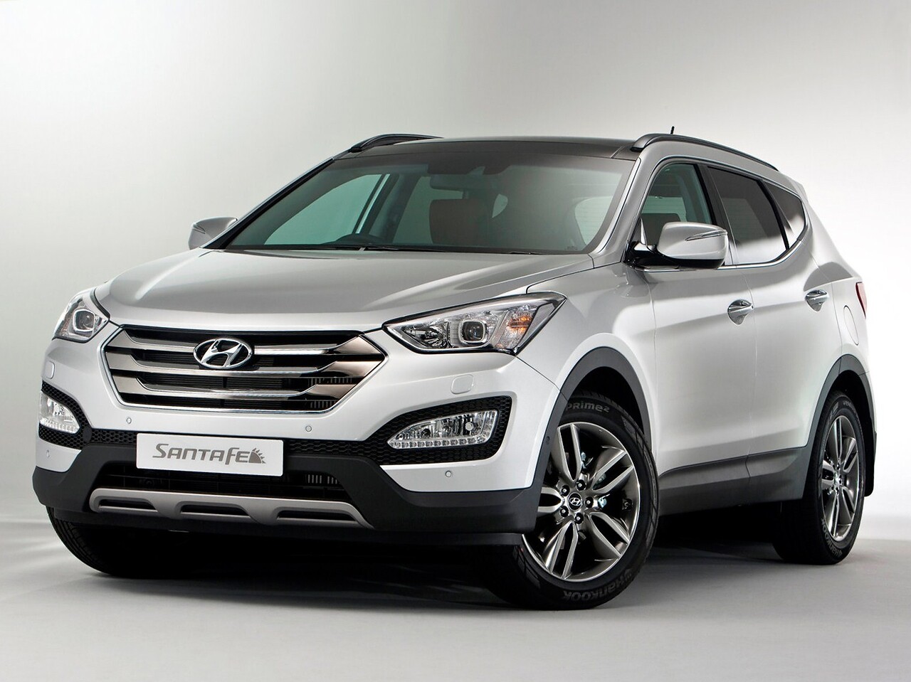 Hyundai Santa Fe (III поколение, 2012 - 2015 г.в.): Серебристый кроссовер на сером фоне, вид спереди сбоку