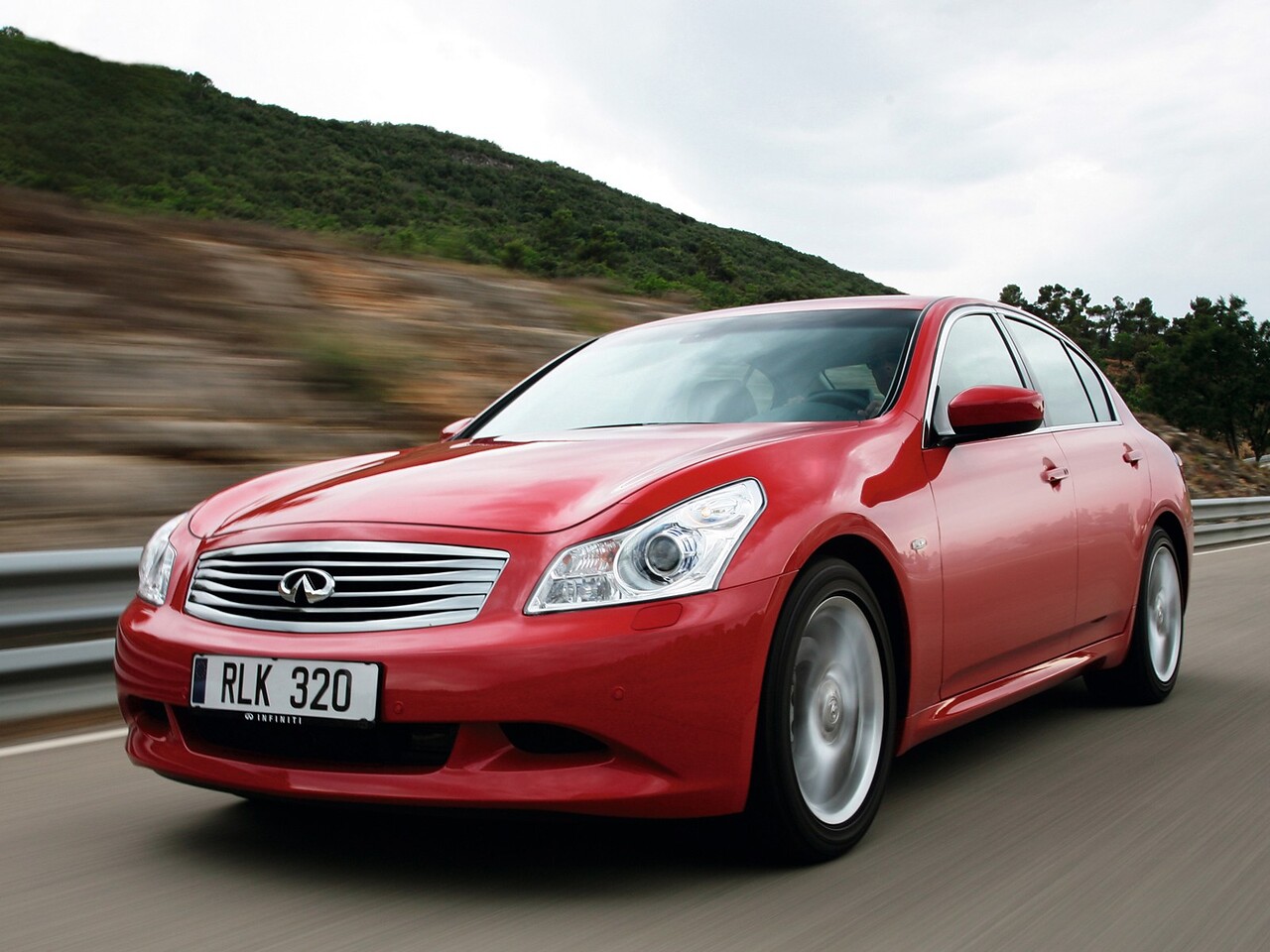 Infiniti G седан (II поколение, 2008 - 2013 г.в.): Красный седан в движении на горной дороге, вид спереди сбоку