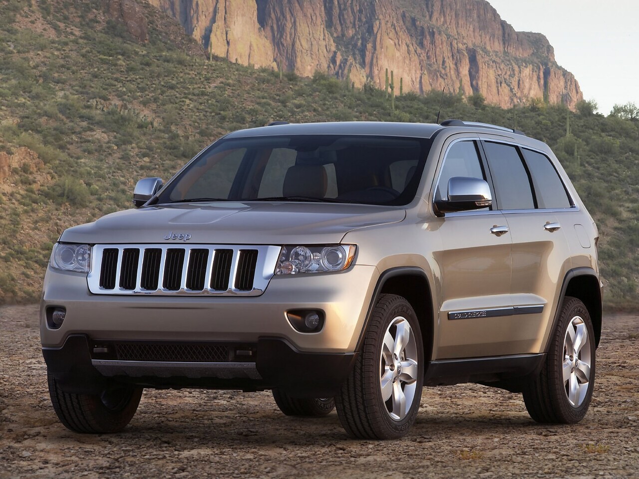 Jeep Grand Cherokee (WK2, 2010 - 2013 г.в.): Три четверти спереди на грунтовой дороге у холмов