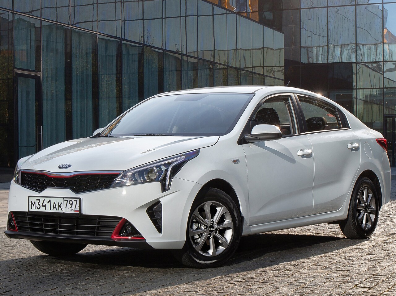 KIA Rio седан (IV поколение рестайлинг, 2020 - 2022 г.в.): Три четверти спереди у стеклянного здания