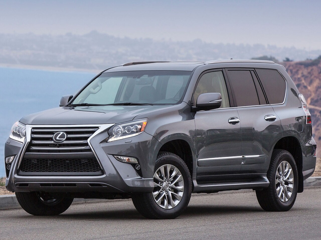 Lexus GX (II поколение рестайлинг, 2013 - 2019 г.в.): Вид спереди сбоку на дороге у побережья