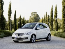 Mercedes-Benz A-Класс хэтчбек 3-дв.: Белый хэтчбек у деревьев, вид спереди сбоку