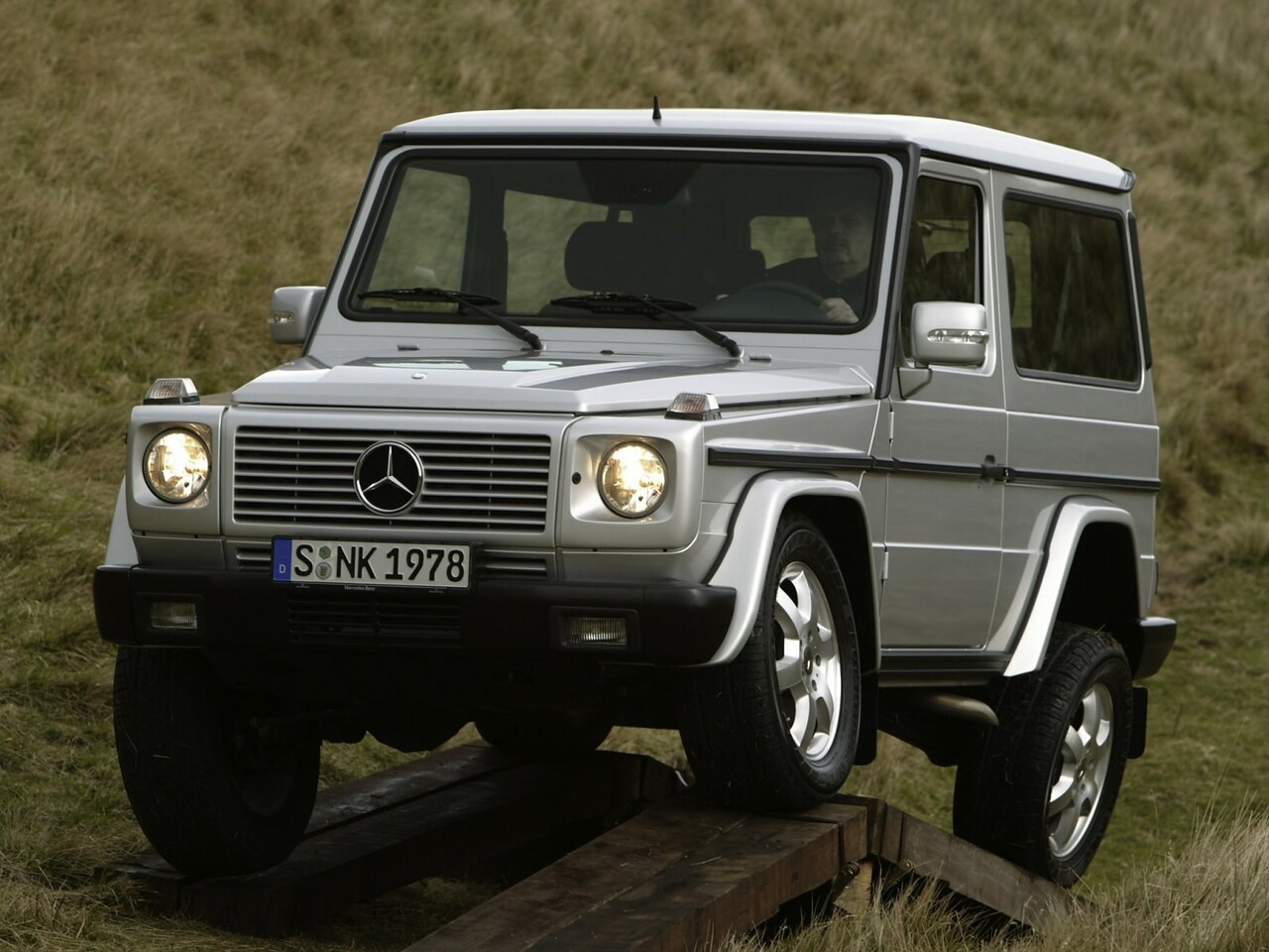 Mercedes-Benz G-Класс 3-дв. 5.5i AT G500 CDI: Серебристый внедорожник на деревянном трамплине, вид спереди сбоку