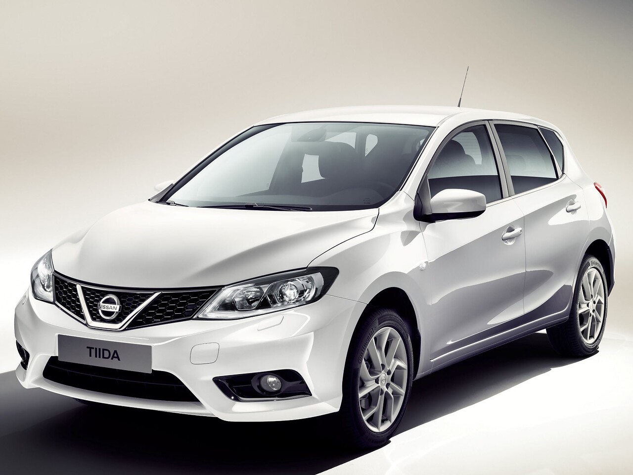 Nissan Tiida хэтчбек 5-дв. (NB17, 2015 - 2016 г.в.): Белый хэтчбек в студии, вид спереди в три четверти