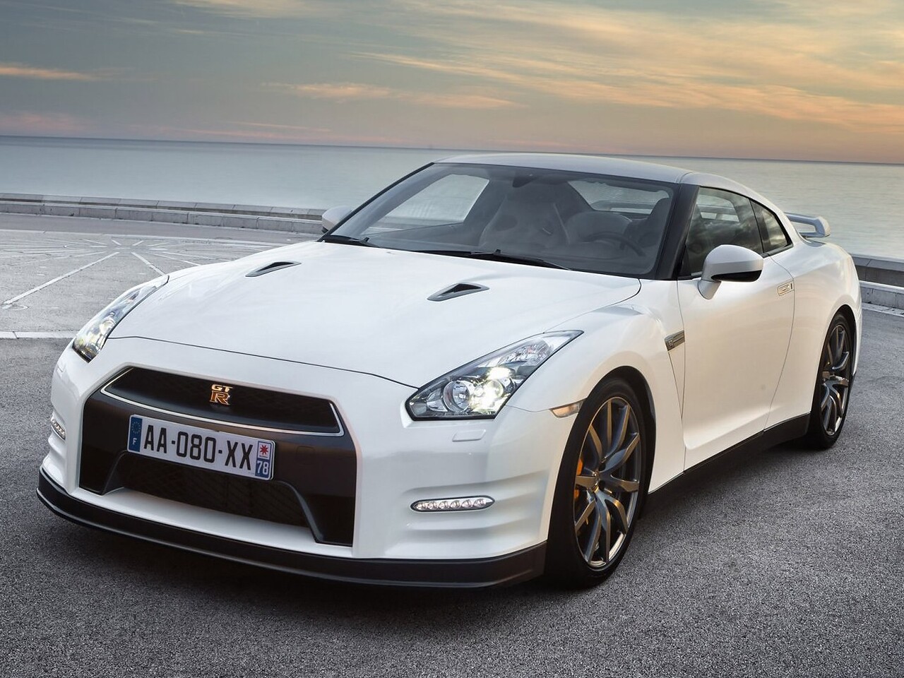 Nissan GT-R (R35 2-й рестайлинг, 2010 - 2012 г.в.): Белый спорткар на берегу моря на закате