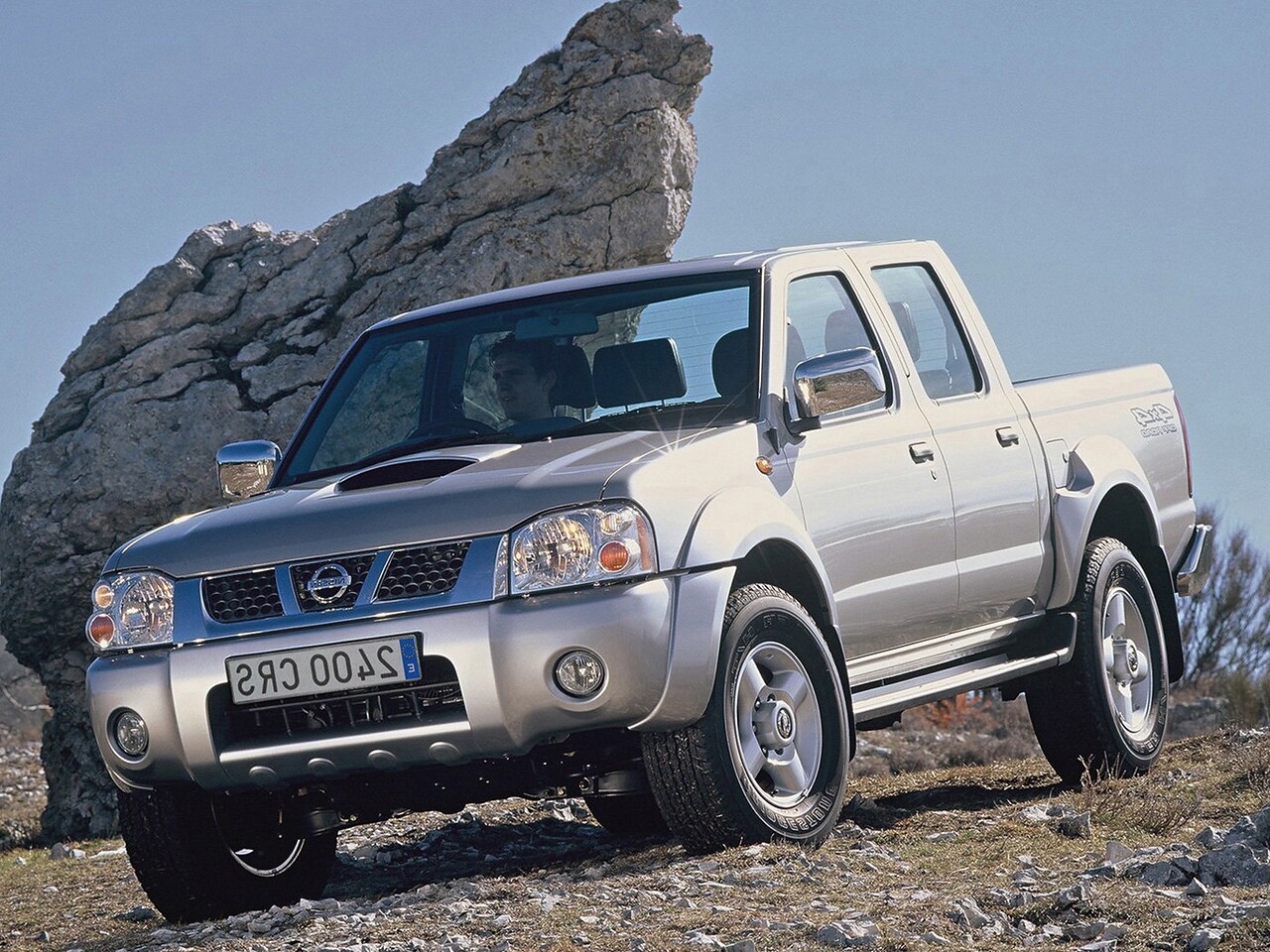 Nissan NP300 (D22, 2008 - 2013 г.в.): Серебристый пикап на каменистой почве у валуна