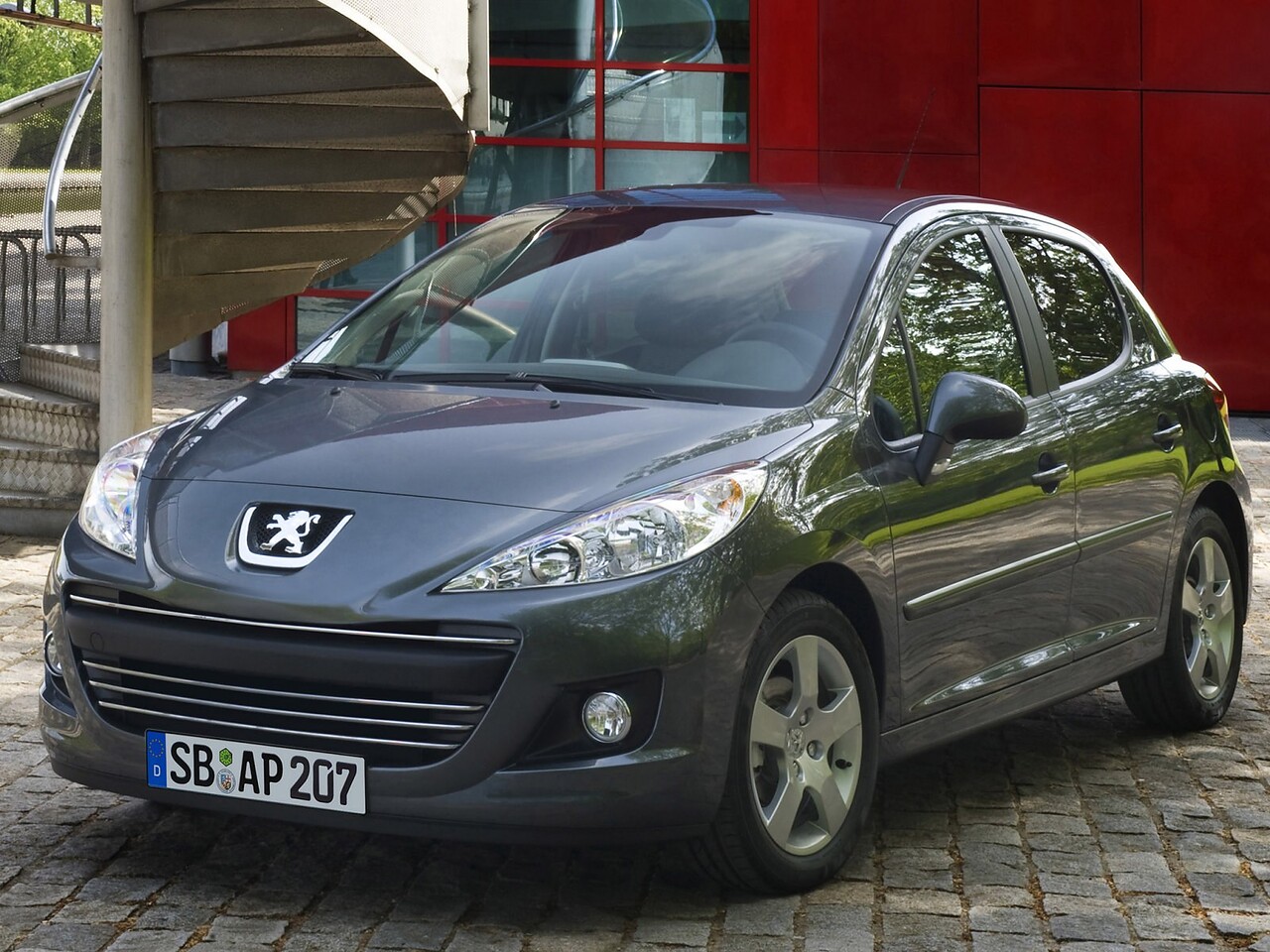 Peugeot 207 хэтчбек 5-дв. (I поколение рестайлинг, 2009 - 2014 г.в.): вид спереди и сбоку на брусчатке