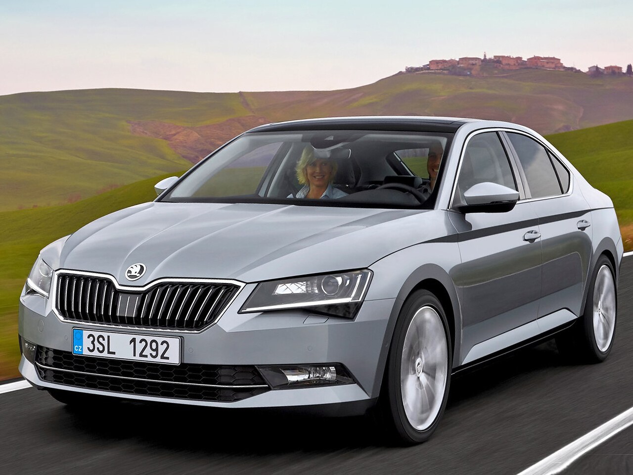 Skoda Superb лифтбек (III поколение, 2015 - 2019 г.в.): Три четверти спереди на дороге у холмов