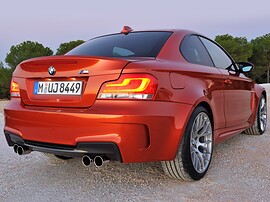 BMW 1-я серия М (E82, 2010 - 2014 г.в.): Оранжевое купе на гравии в сумерках, вид сзади сбоку