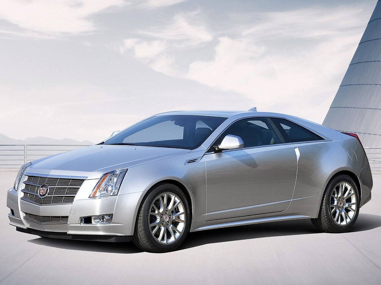 Cadillac CTS купе 3.6 4x4 AT: Серебристое купе у светлого здания, вид спереди сбоку