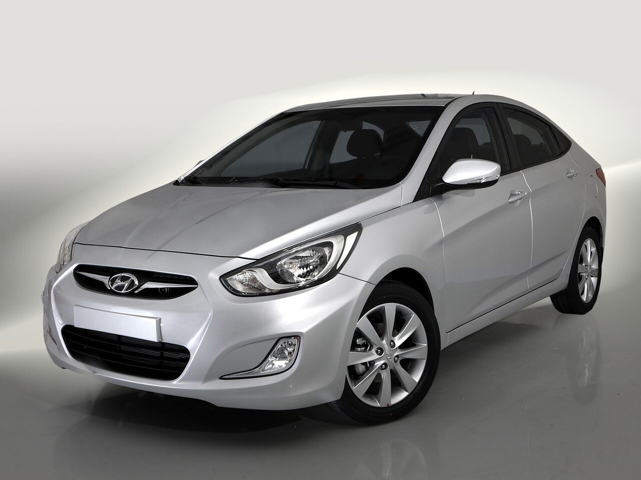 Hyundai Solaris седан (I поколение, 2010 - 2014 г.в.): Серебристый седан в студии, вид спереди сбоку
