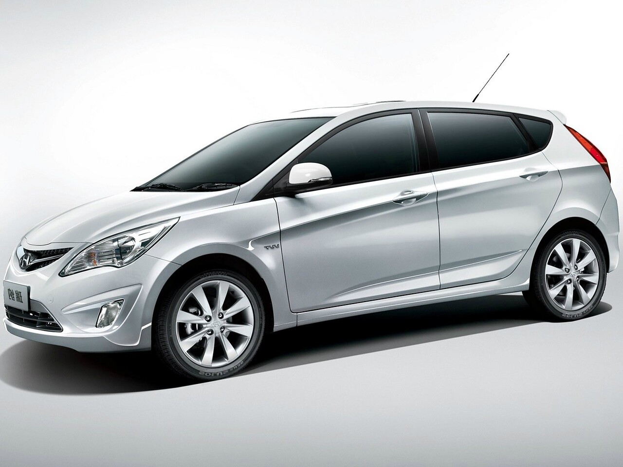 Hyundai Solaris хэтчбек 5-дв. (I поколение рестайлинг, 2014 - 2017 г.в.): Три четверти спереди в студии, серебристый кузов