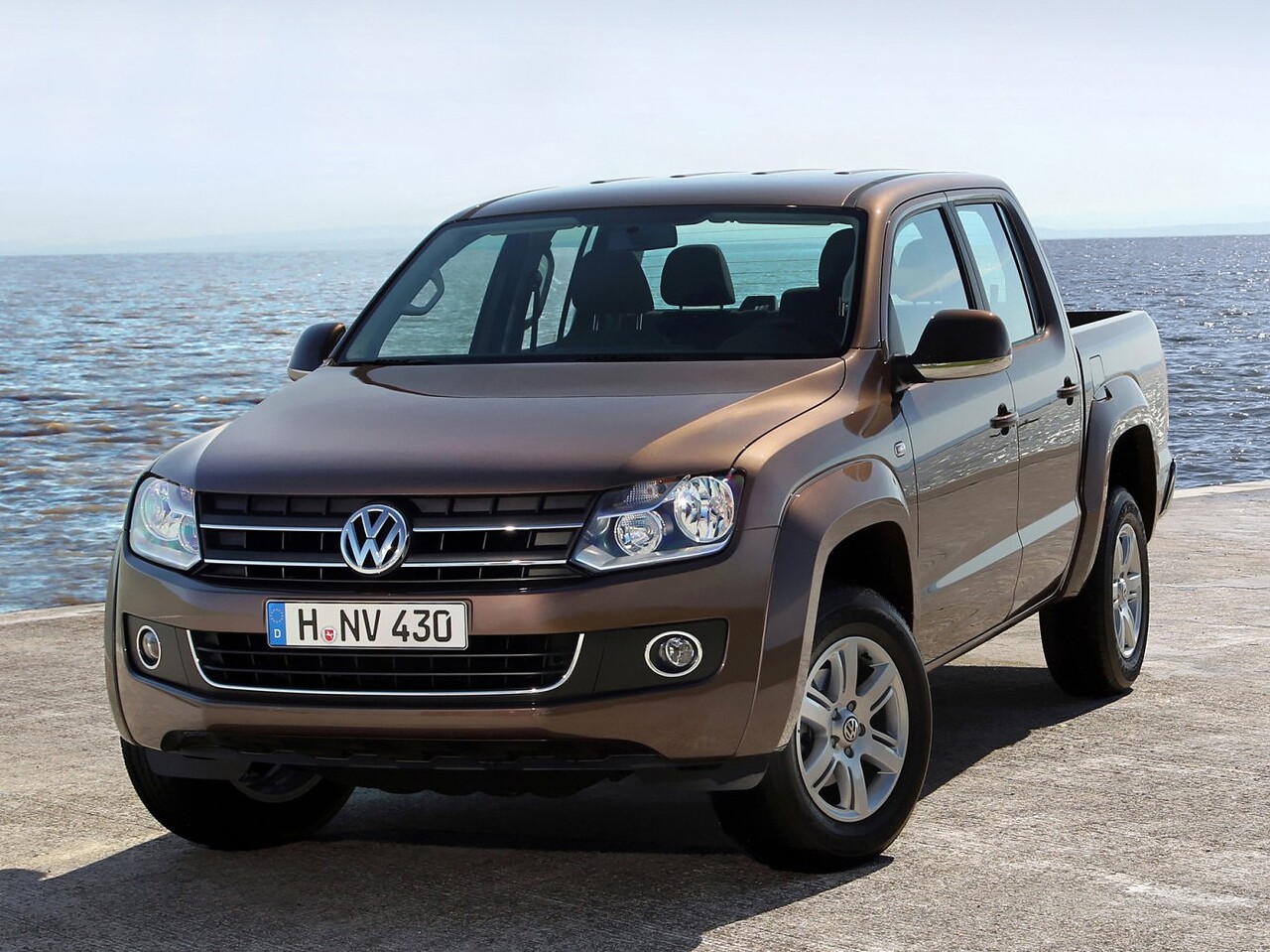 Volkswagen Amarok (I поколение, 2010 - 2016 г.в.): Три четверти спереди у воды, коричневый кузов