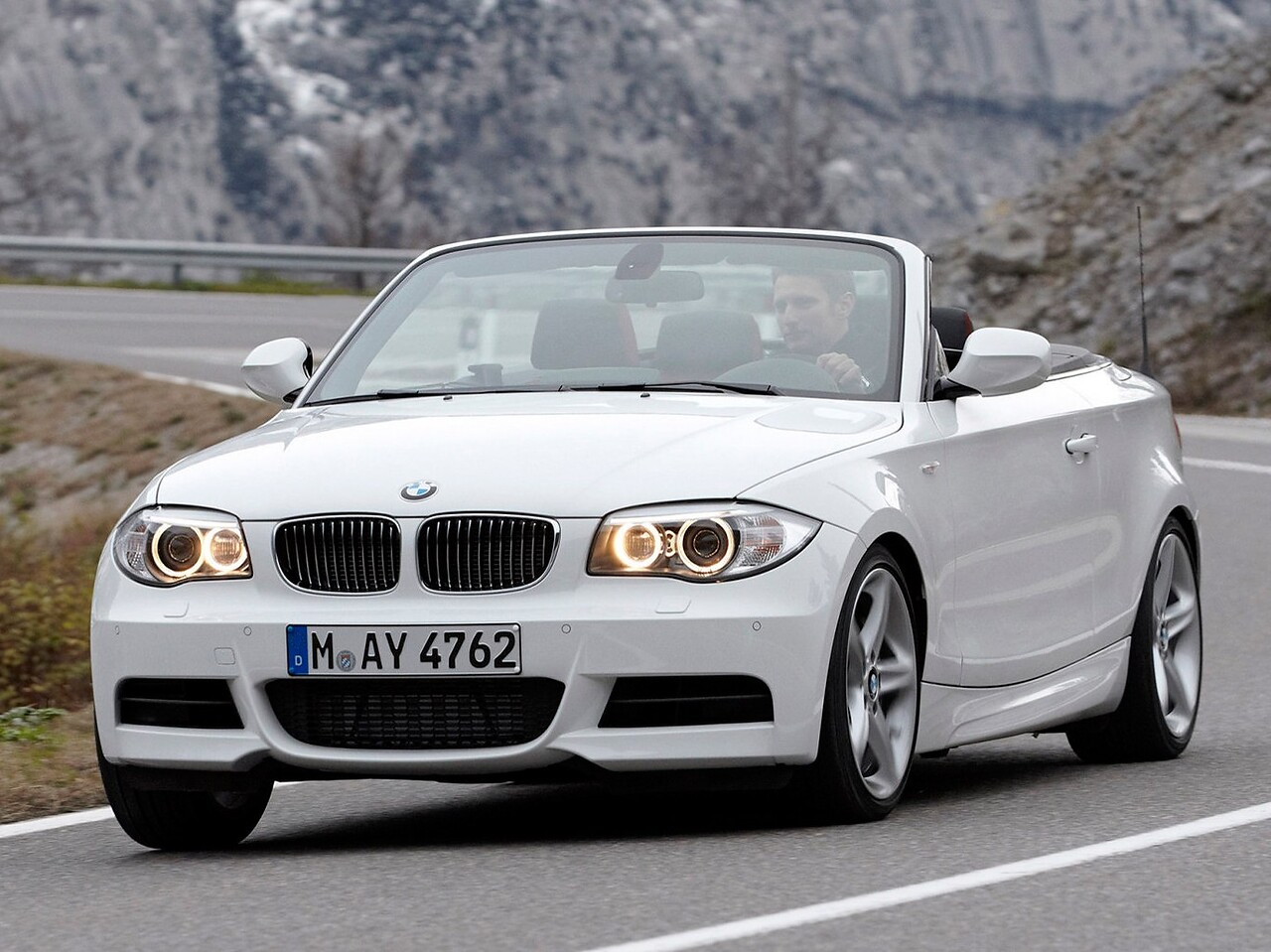 BMW 1-я серия кабриолет (E88 рестайлинг, 2011 - 2013 г.в.): вид спереди сбоку с открытым верхом в движении