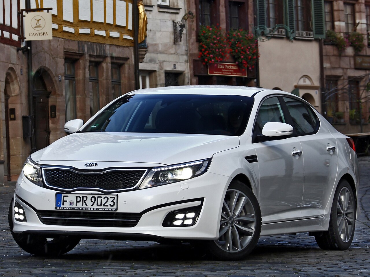 KIA Optima (III поколение рестайлинг, 2014 - 2016 г.в.): вид спереди сбоку у здания