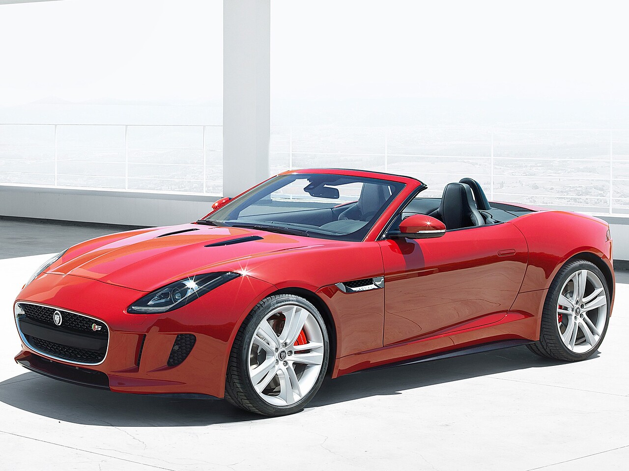 Jaguar F-Type родстер (I поколение, 2013 - 2016 г.в.): вид спереди сбоку на светлом фоне