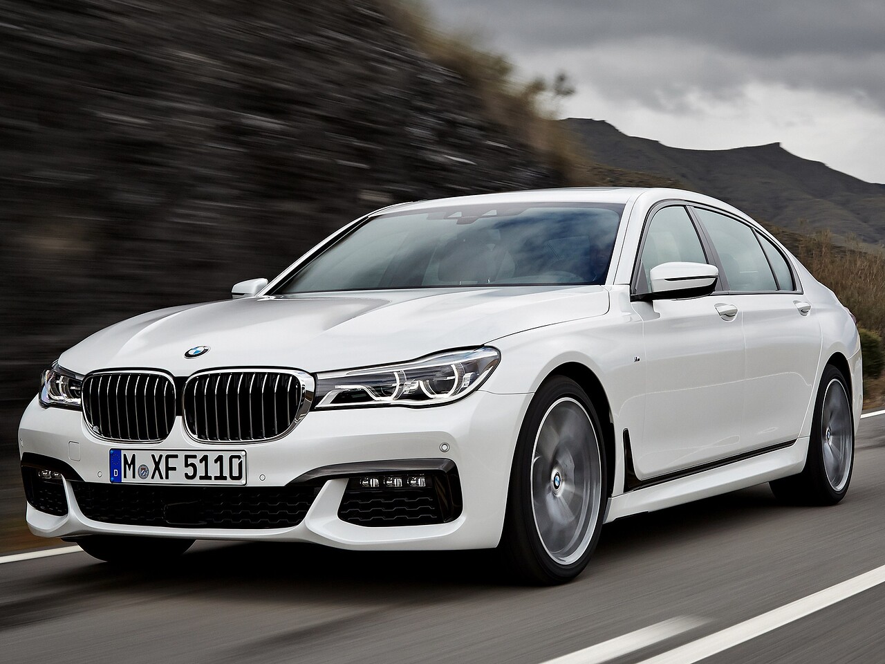 BMW 7-я серия 4.4 xDrive MT 750i: вид спереди сбоку на извилистой дороге среди холмов
