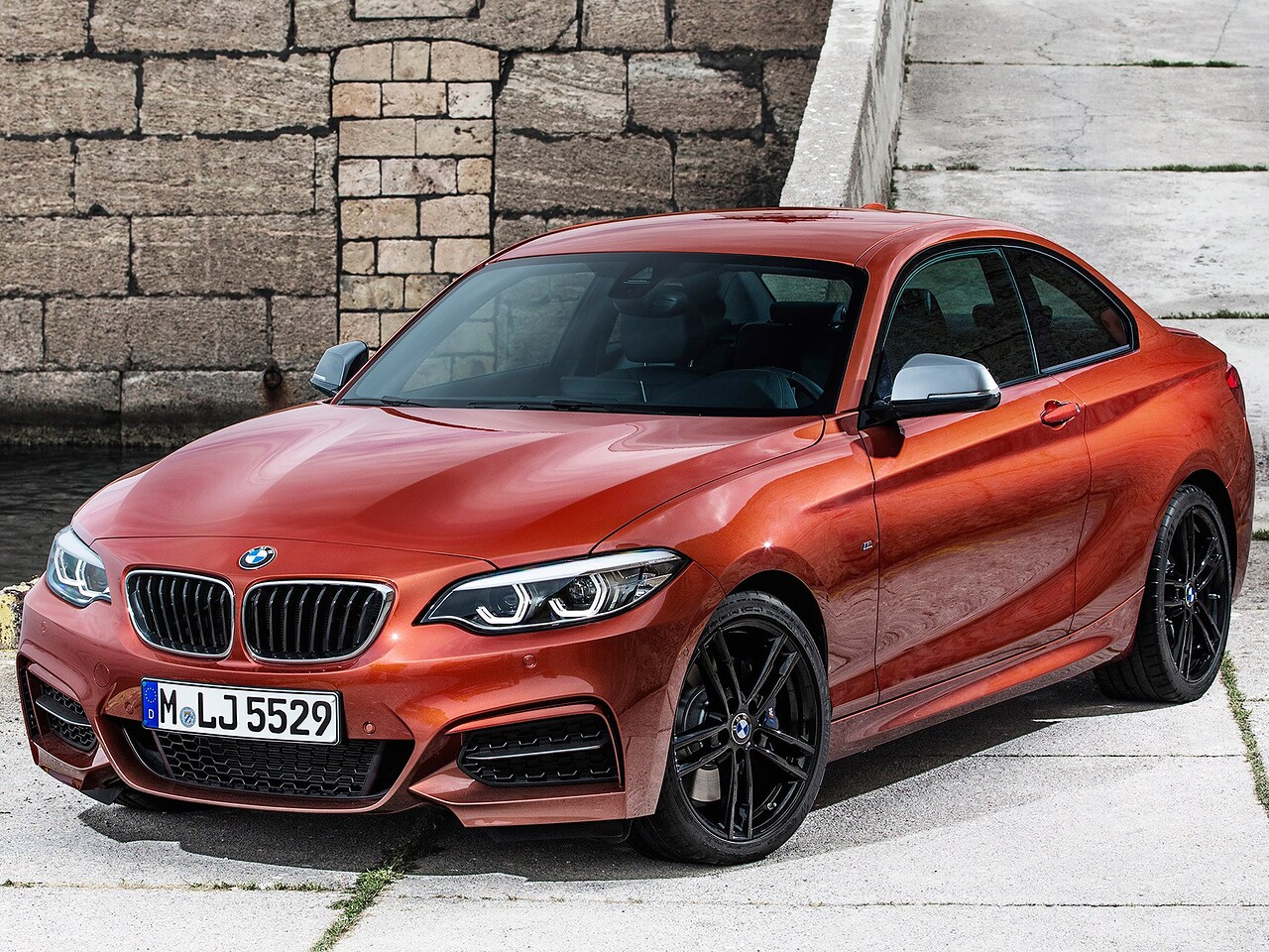 BMW 2 купе 3.0 AT Base (M240i xDrive): вид спереди сбоку у каменной стены