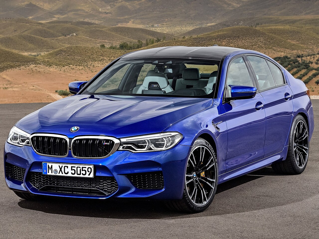 BMW M5 седан (F90, 2017 - 2020 г.в.): Синий седан на фоне гор